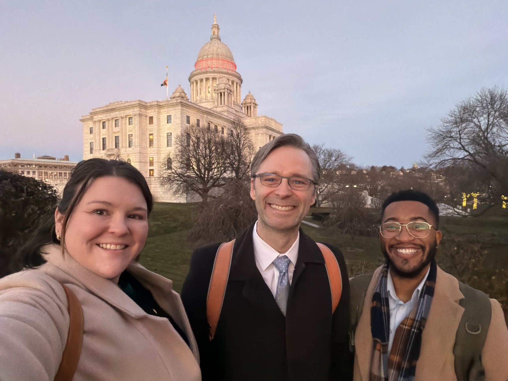 Three people in front of the Rhode Island Capitol