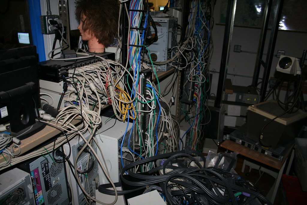 A cluttered room filled with a large number of computers, cables, and various media equipment
